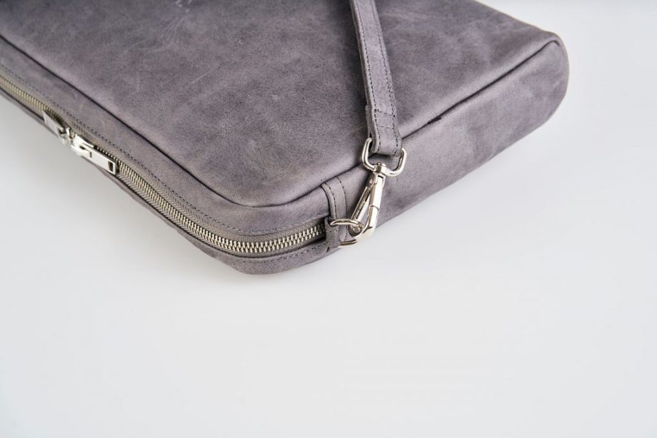 Zoom Product Picture side top view of a lying down blue vegetable tanned leather shoulder bag with a double silver zipper opening and an detachable shoulder strap lying on top of the bag