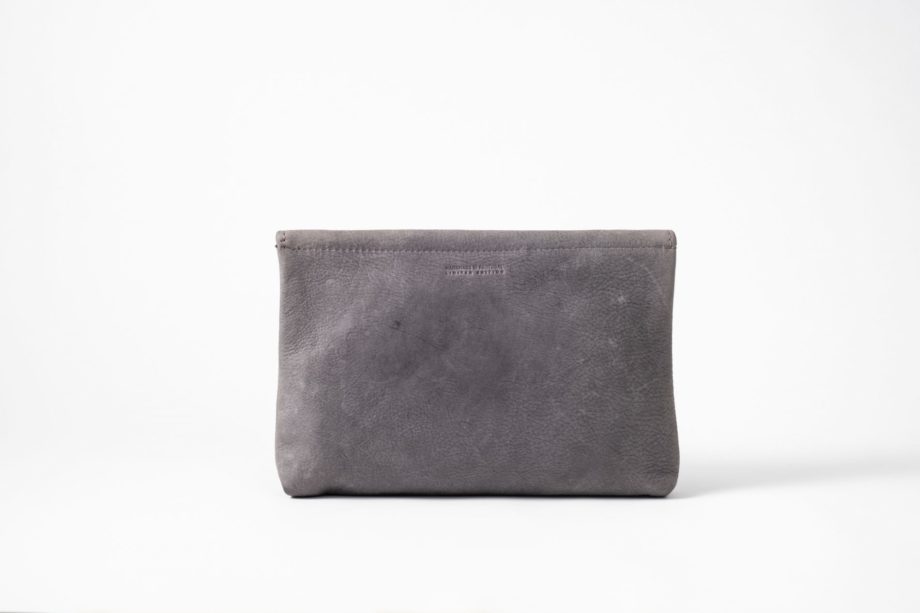 Back view on an upstanding blue-greyish vegetable tanned Leather Clutch with invisible magnet opening and only one seam in the back top of the bag