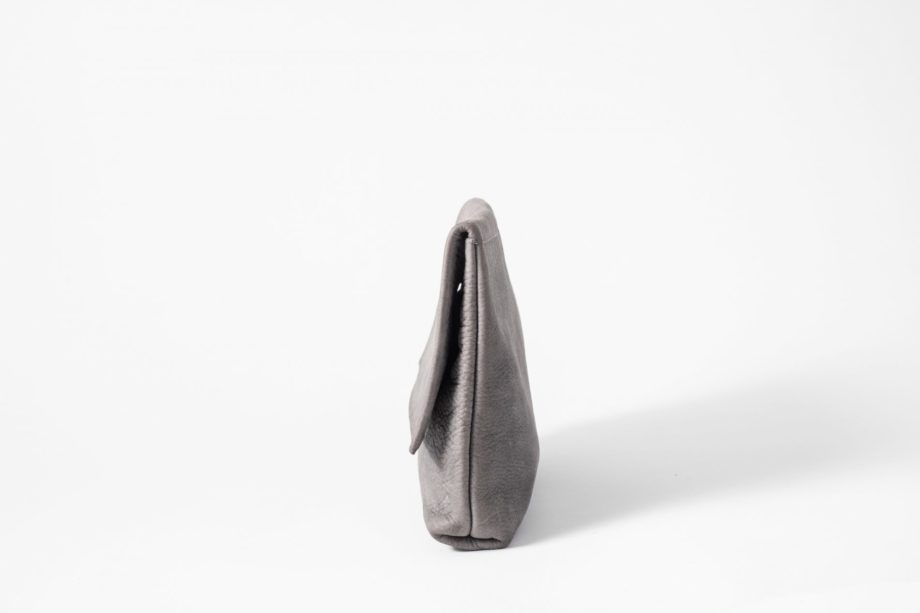 Side view on an upstanding blue-greyish vegetable tanned Leather Clutch with invisible magnet opening