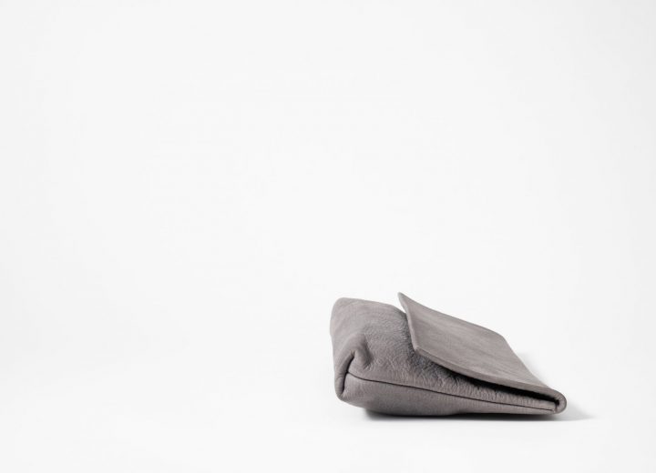 side view on a lying down Clutch made of blue-greyish vegetable tanned leather